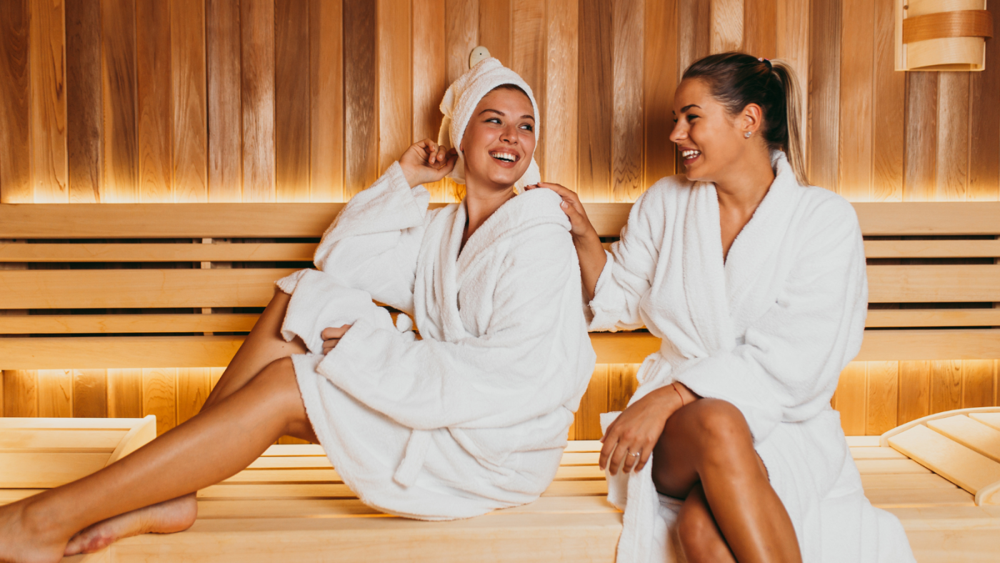 Two smiling women in a sauna.