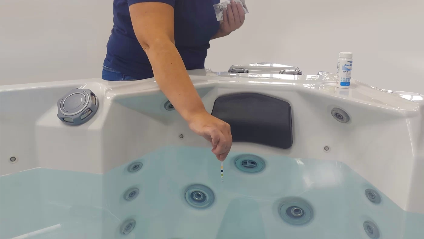 Ženska, ki pomaka testni trak v vodo masažnega bazena.